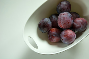 Violet plums in a white bowl