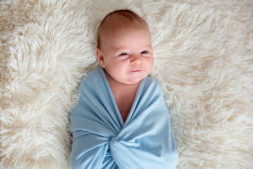 Newborn baby boy, holding a little guitarand smiling