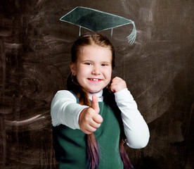 cute little schoolgirl against chalkboard, with drawn  cap