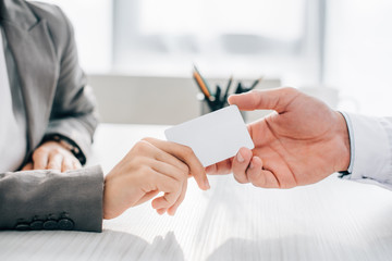 cropped image of patient giving id card to doctor in clinic