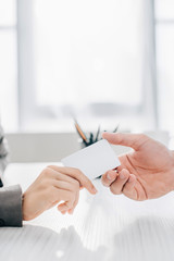 cropped image of patient giving business card to doctor in clinic