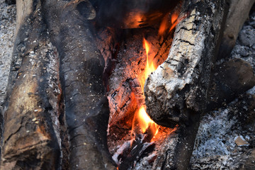 Blaze of bonfire, wood fire flame heat spires burning in fireplace with smoke close up