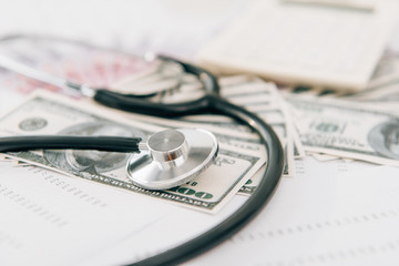 selective focus of stethoscope and dollar banknotes on table in clinic, health insurance concept