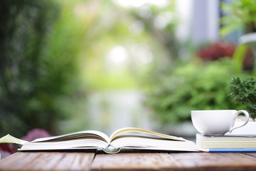 White coffee cup with notebooks on wooden table at outdoor