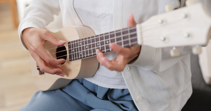 Woman play ukulele at home