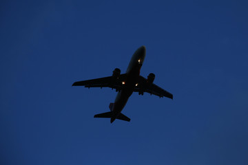 The airplane is flying against the blue sky in the sun