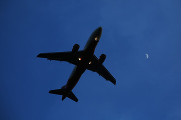 The airplane is flying against the blue sky in the sun