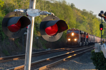 Close up of an active railroad crossing light with blurred on-coming train in background.