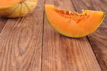 Piece of sugar cantaloupe melon on wooden surface, with copy space