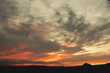 Evening sky after sunset with red clouds and the silhouette of the private sector of a small town
