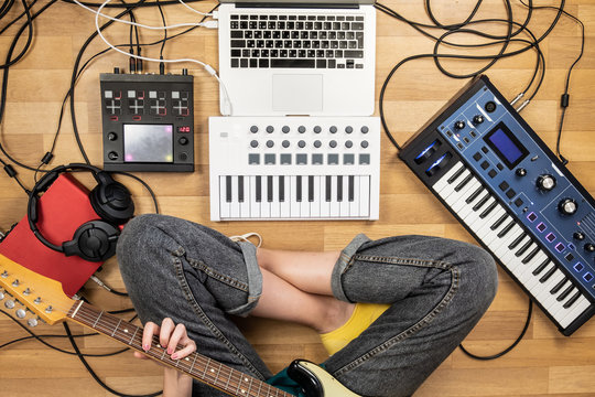 Young Woman Playing Electric Guitar, Point Of View Shot. Top View Of Female Producer At Home Studio Recording Guitar And Electronic Instruments.