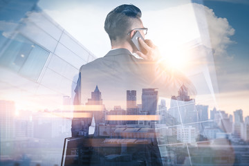 The double exposure image of the businessman using a smartphone during sunrise overlay with...
