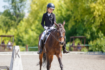Teenage girl riding bay horse performing dressage test on equestrian competition