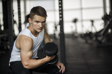 Handsome man lifting dumbbell at gym