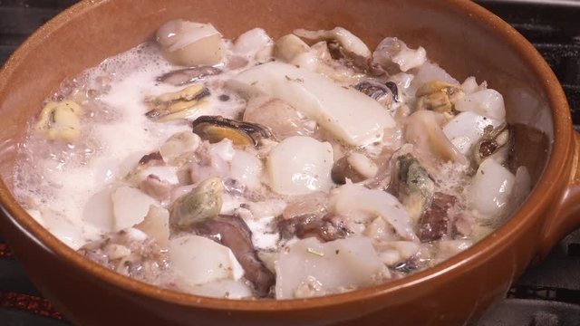 Seafood chowder boiling in a clay pan in UHD