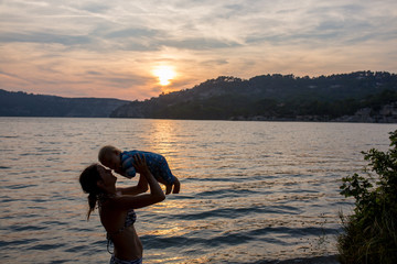 Cute child, toddler boy, enjoying the sunset over a lake