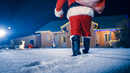 Santa Claus Carrying Red Bag over the Shoulder, Walks into Front Yard of the Idyllic House...