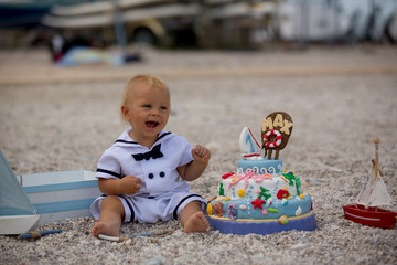 Sweet baby boy, celebrating first birthday with sea theme cake and decoration