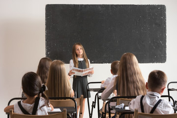 School children in classroom at lesson. The little boys and girls sitting at desks. Back to school,...