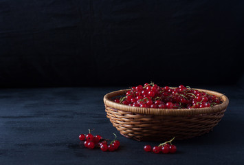 red currant berries in a basket on a black background