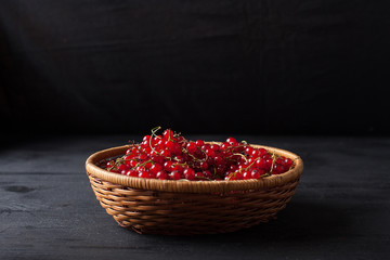 red currant berries in a basket on a black background