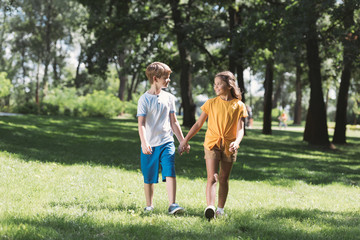 Fototapeta premium beautiful happy children holding hands and walking together in park