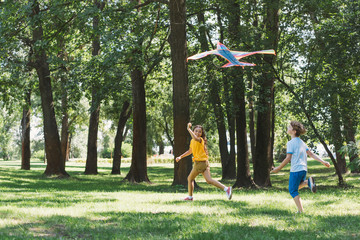 cute happy children playing with colorful kite in park
