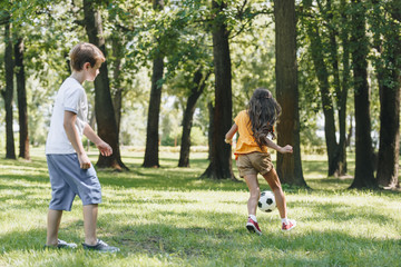 cute little kids playing with soccer ball in park