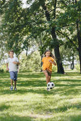 Obraz na płótnie Canvas cute happy kids playing with soccer ball in park