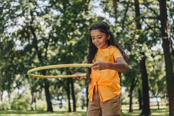beautiful happy child playing with hula hoop in park