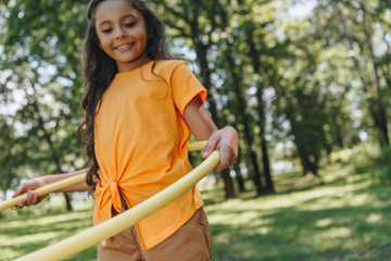 cute smiling child playing with hula hoop in park