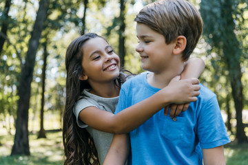 Obraz premium cute happy children hugging and smiling in park
