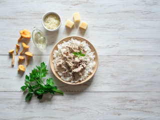 Risotto with mushrooms chanterelles on a plate on a wooden white table.
