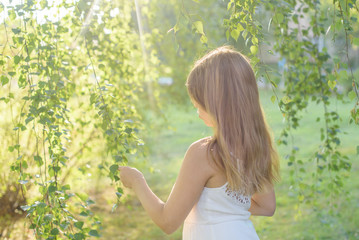 beautiful girl in a white dress stands in the sun rays. 