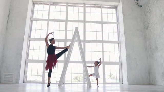 small ballerina repeats the movement in her ballet class for her teacher