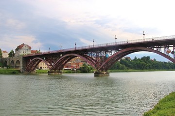 Fototapeta na wymiar Maribor, Slovenia - July 6, 2018: The Old Bridge, or State Bridge, across the Drava river, in Maribor, Slovenia. 270 meters long, opened in 1913, with three steel arches. South-east Europe.