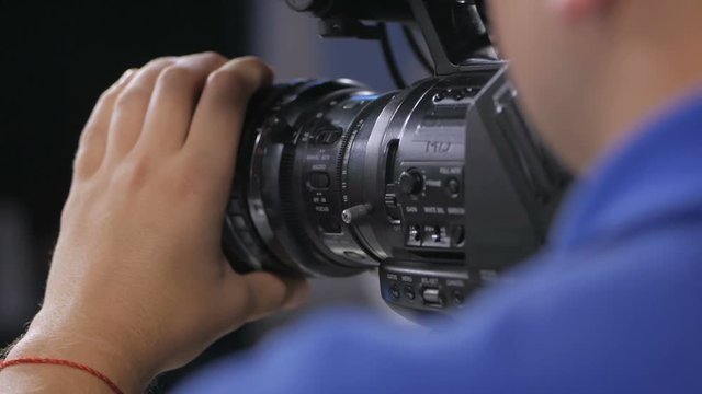 Camera operator working with a cinema broadcast TV camera. Back view