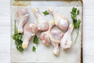Uncooked raw chicken legs on a baking sheet paper on tray, top view. Flat lay, overhead, from above.