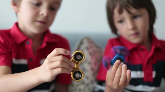 Little children, boy brothers, playing with colorful fidget spinner toys