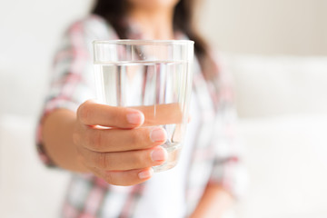 Happy beautiful young woman holding drinking water glass in her hand. Health care concept.