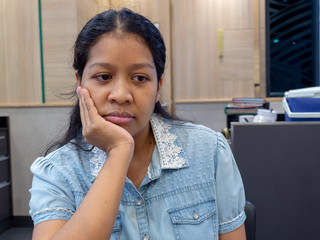 Asian women wearing jacket blue jeans make a boring face in the restaurant after waiting for a long time dating partner.