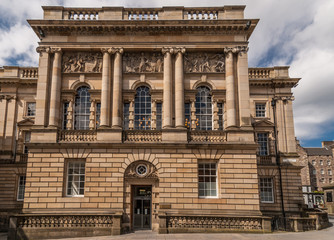 Edinburgh, Scotland, UK - June 14, 2012; Massive cube-like Edinburgh Lothian Chambers building in yellow to beige stones with pillars and frescoes. Blue sky with white clouds.