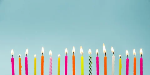 Foto op Plexiglas Set of many different color shape and pattern birthday candles burning in long row, isolated on blue. Happy Birthday card design concept.  © FotoHelin