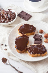 Sandwiches with chocolate hazelnut spread on the plate. Cup of coffee on the table.