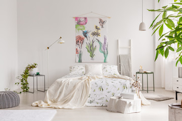A bright eco friendly bedroom interior with a bed dresses in green plants pattern white linen....