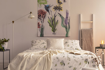 Flowers and a hummingbird painted on the fabric above a bed which is dressed in green plants...
