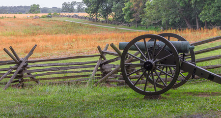 Fototapeta na wymiar A single Cannon at Gettysburg PA by a split log fence