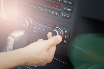 Man adjusting car air conditioning system. Closeup, natural lighting, flare.