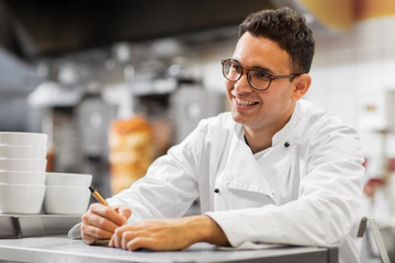 people, fast food and cooking concept - happy smiling chef at kebab shop writing order