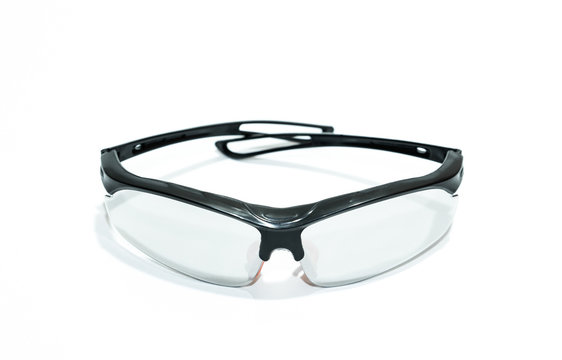Close up view. Protective glasses with black plastic frame isolated on white floor.
